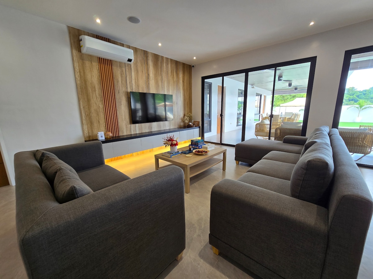 Modern living room with large sofas, smart TV, and wood accent wall