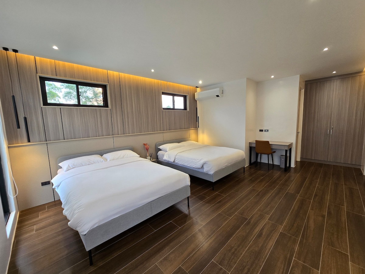 Primary bedroom with two queen beds and wood panel accent wall